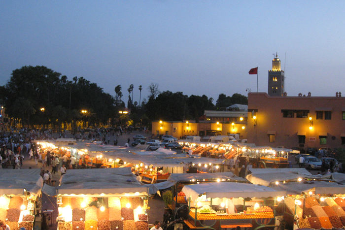 Plads Jemaa el Fna i Marrakech i skumringen set oppe fra restaurant Argana. I forgrunden ses boder med tørrede frugter og friskpresset juice. I baggrunden Koutoubia minareten.