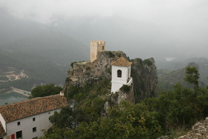 Det lille klokketårn og den gamle borg Castell de Guadalest på toppen af klipperne i byen Guadalest. Til venstre i billedet skimtes den store inddæmmede sø.
