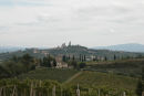 Landskabet i Toscana er meget afvekslende med vinmarker, oliventræer, cypresser, pinjetræer og anden skov. Det er middelalderbyen San Gimignano, man ser oppe på toppen af bakken. 
