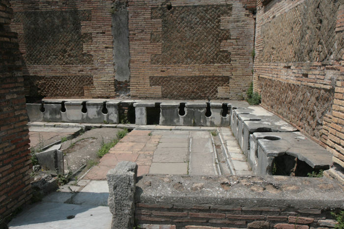 Selv for flere tusinde år siden havde man rindende vand og opvarmning af badstuer. Man havde også toiletter. Her et fælles toilet i Ostia Antica, hvor der kunne sidde ca. 25 personer.