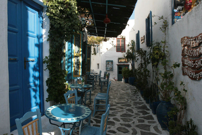 En af de smalle gader i Chora på Amorgos. Det var en meget siestadød by; men efter lidt søgen fandt vi et sted, hvor vi kunne få lidt at drikke. Det var her ved de små blå borde.
