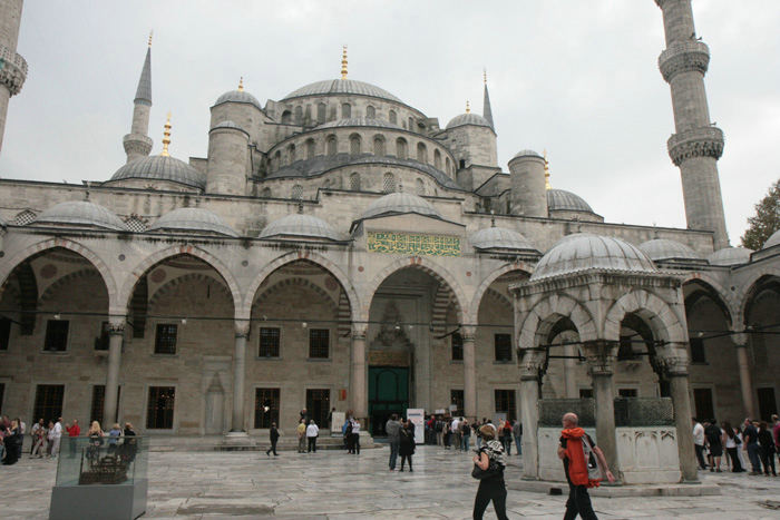 Den Blå Moske i Istanbul, set inde fra den lukkede gård. Indgangen midt i billedet med køen af besøgende, der venter på at komme ind.  