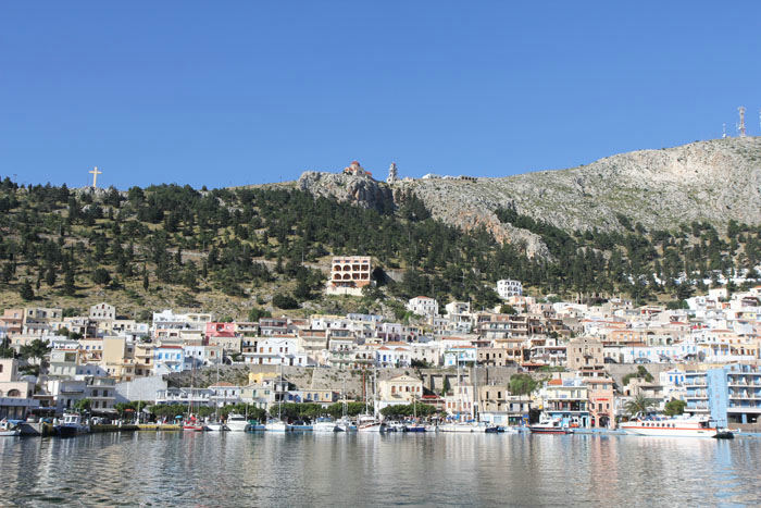 Pothia på Kalimnos set ude fra vandet. Oppe på toppen af klipperne ses det store kors og Agios Savas-klosteret. 