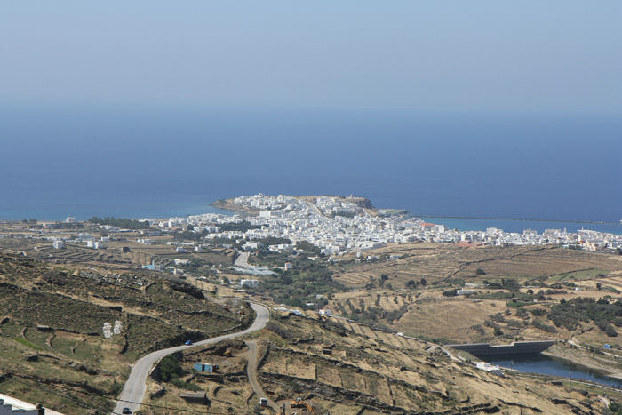 Tinos by set oppe fra vejen, der fører nord på. Havnen til højre er beskyttet af en meget lang mole.  