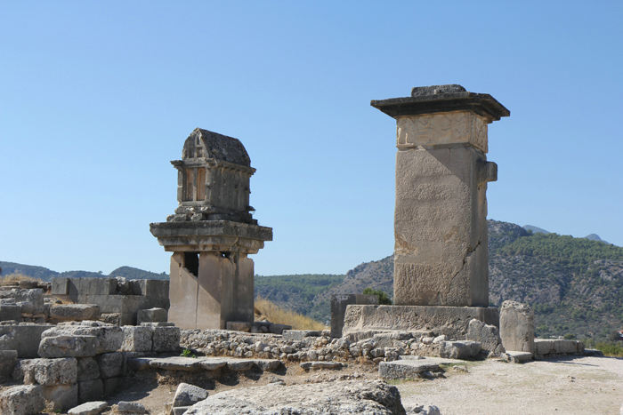 Til højre ses Harpy monumentet, der er fra det 5. århundrede BC. Til venstre et andet lykisk gravkammer, der er placeret på en søjle. Sidstnævnte er dateret fra det 4. århundrede BC.