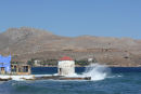 Den gamle vindmølle, der står ude på en klippe i havnen Agia Marina på Leros, får nogle sprøjt i den høje sø. 