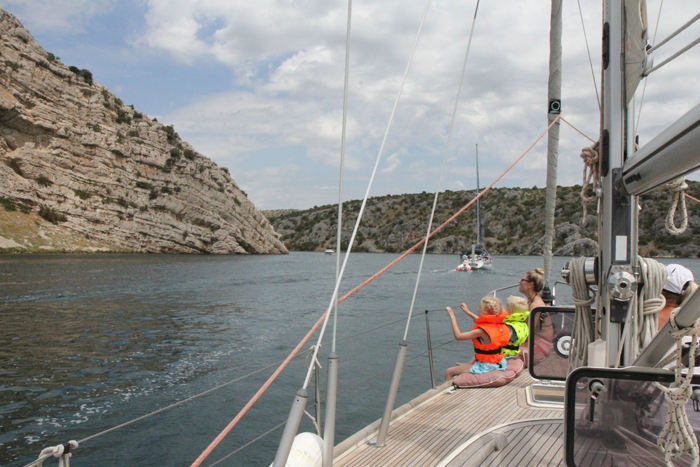 Julie, Kasper og Maiken nyder udsigten på fordækket på vej ind ad floden Krka til marinaen i Skradin.