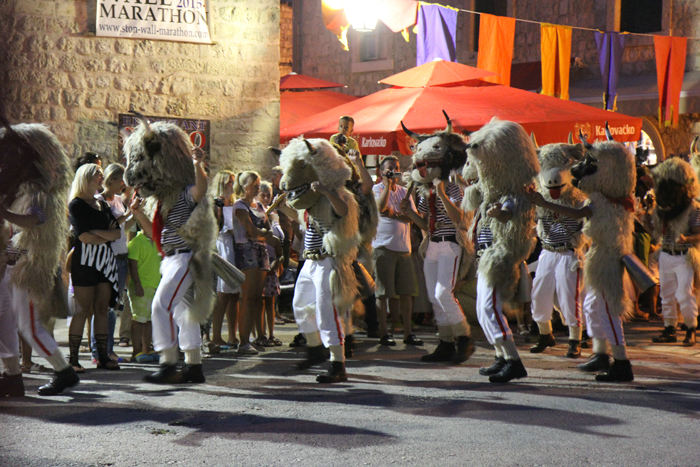 Der var karneval i Ston, mens vi lå der. Her er det ’klokkemændene’, der er på scenen. De havde en kobjælde/klokke hængende omme bag på; det gav en del larm.  