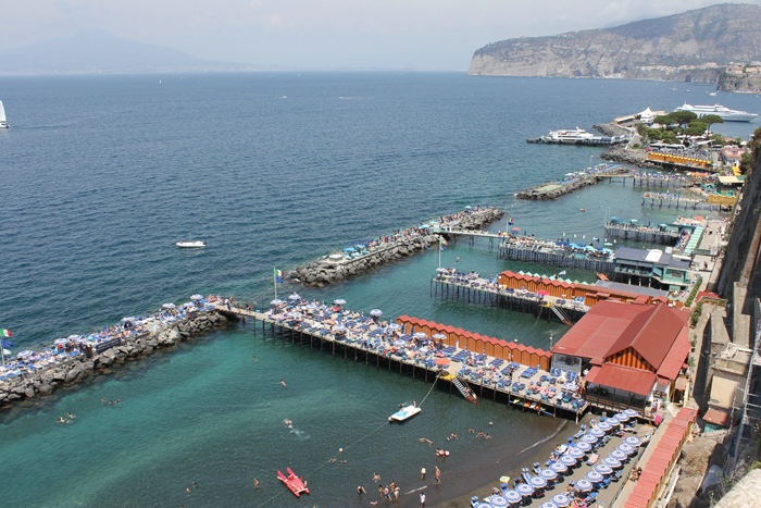 De fleste ’badestrande’ i Sorrento er anlagt på pæle. Til højre ses den lille havn, hvor der ikke var plads til en så lille båd som vores. Vi forsøgte, men desværre var alt reserveret, selv om der var masser af ledige pladser.  