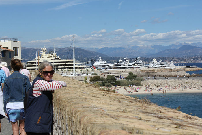 Skipperinden nyder udsigten fra den gamle bymur ud over badestranden i Antibes og med millionærkajen med de enorme lystbåde i baggrunden.