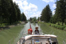 Skipperinden ved roret på Canal entre Champagne et Bourgogne. Vi må indrømme, at vi manglede en bom til at hænge vort solsejl op i eller en bimini, men vi klarede os med en bredskygget hat. 